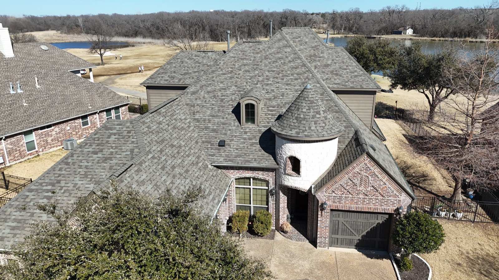 Drone view of a new roof on a lakeside home with a stone turret